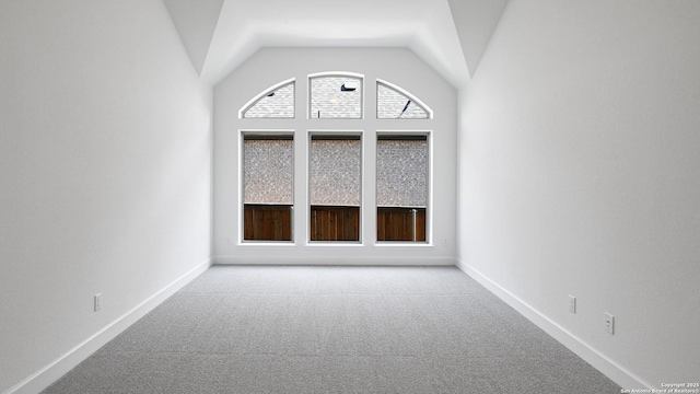 carpeted empty room with baseboards and high vaulted ceiling