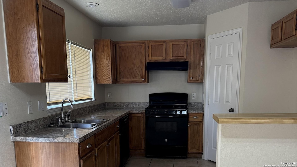 kitchen with light tile patterned flooring, sink, a textured ceiling, and black appliances