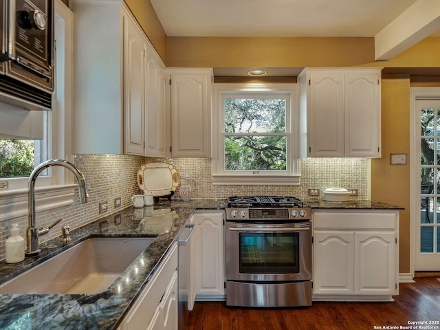 kitchen featuring dark stone countertops, stainless steel appliances, sink, and white cabinets