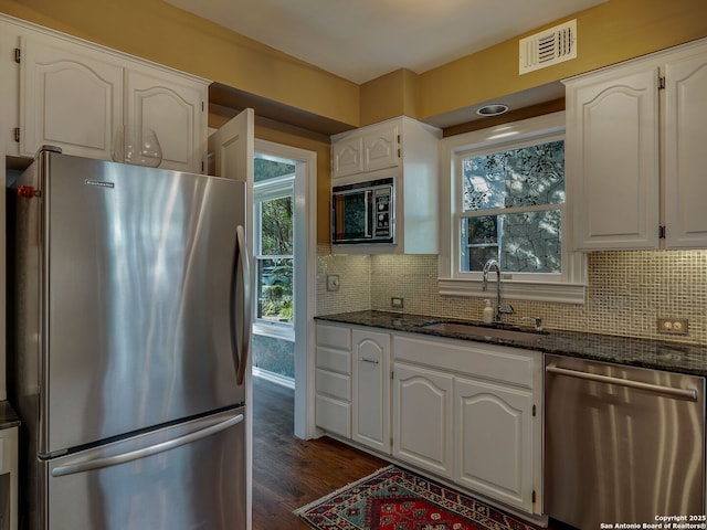 kitchen with white cabinetry, appliances with stainless steel finishes, sink, and dark stone counters