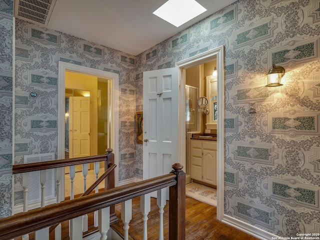 corridor with a skylight and dark hardwood / wood-style floors