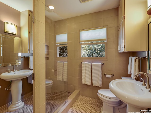 bathroom featuring toilet, tile patterned flooring, sink, and tile walls