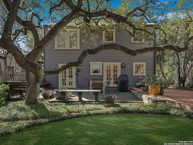 back of house featuring french doors and a lawn