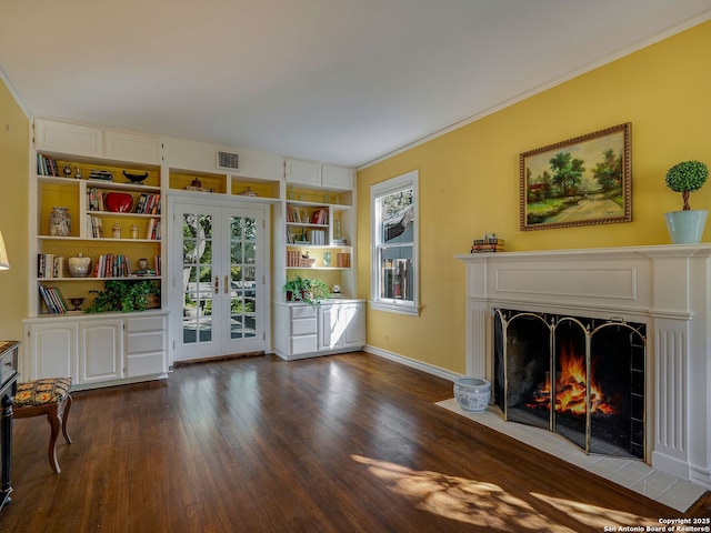 living room with french doors, crown molding, dark wood-type flooring, and built in features