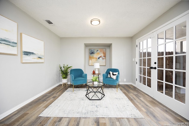 living area with hardwood / wood-style floors, french doors, and a textured ceiling