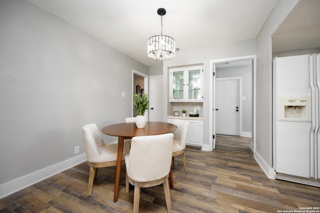 dining space with dark hardwood / wood-style flooring, a chandelier, and a textured ceiling