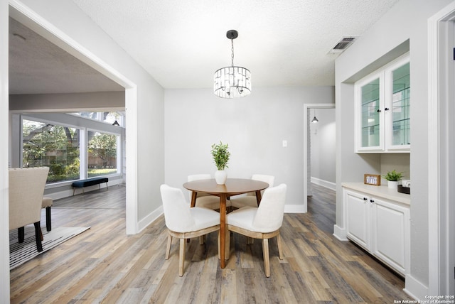 dining space with hardwood / wood-style floors, a notable chandelier, and a textured ceiling