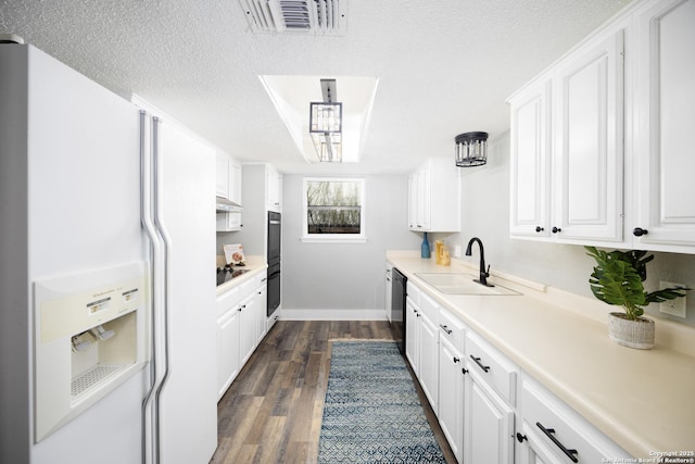 kitchen featuring sink, dark wood-type flooring, black appliances, a textured ceiling, and white cabinets