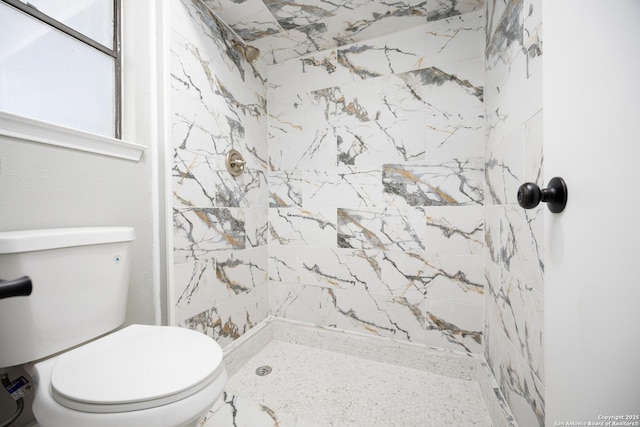 bathroom featuring a tile shower and toilet