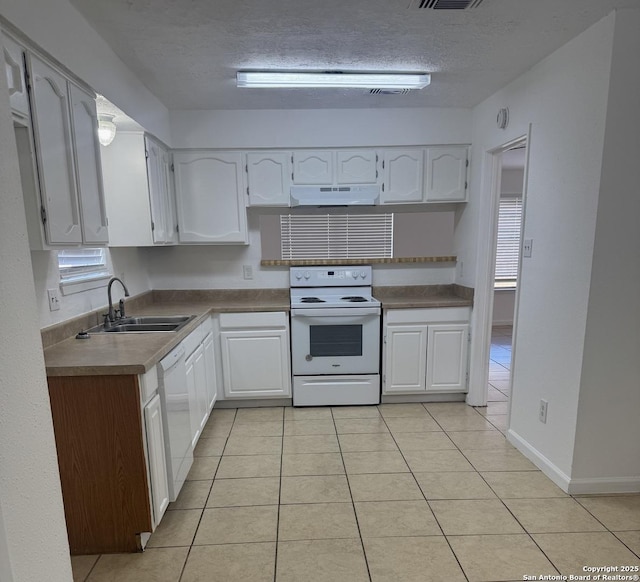 kitchen with white cabinetry, white appliances, a textured ceiling, and light tile patterned floors