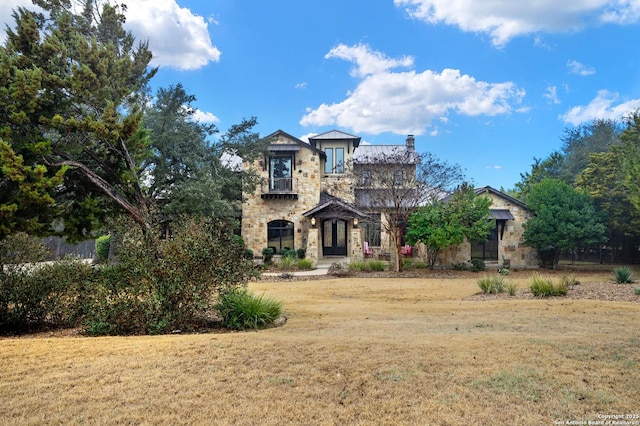 view of front of house with stone siding, a front lawn, and a chimney