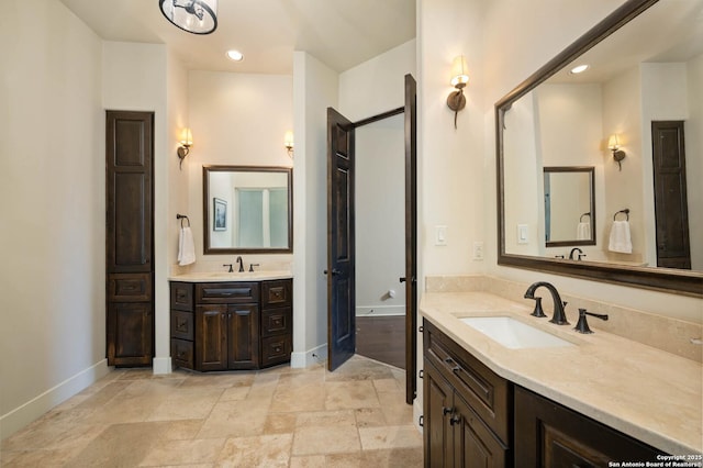 bathroom featuring baseboards, two vanities, and a sink