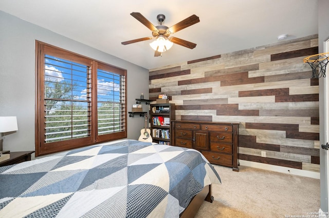 bedroom with light carpet, wood walls, an accent wall, and baseboards