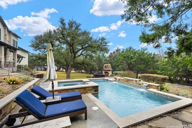 view of swimming pool with a pool with connected hot tub, an outdoor stone fireplace, and a patio