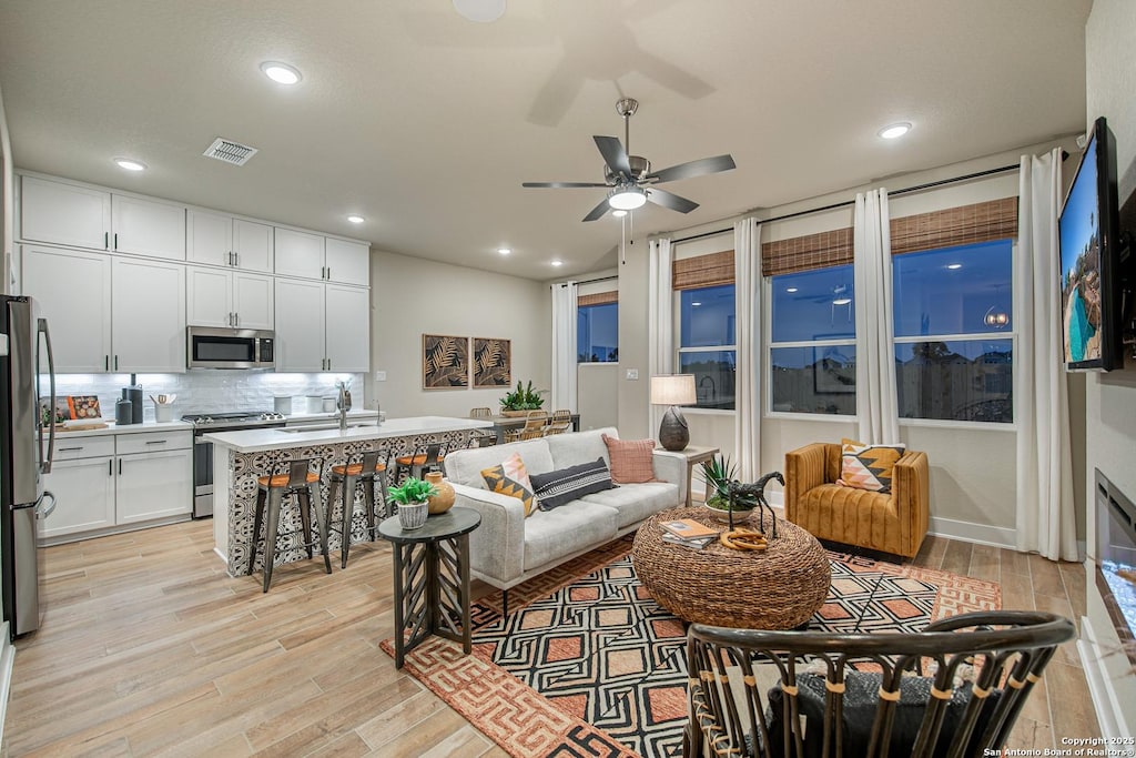 living room with sink, light hardwood / wood-style flooring, and ceiling fan