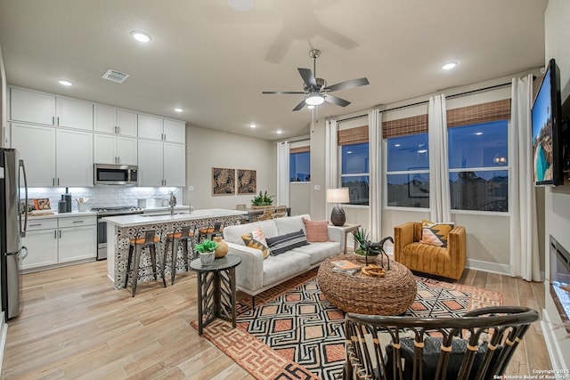 living room with sink, light hardwood / wood-style flooring, and ceiling fan