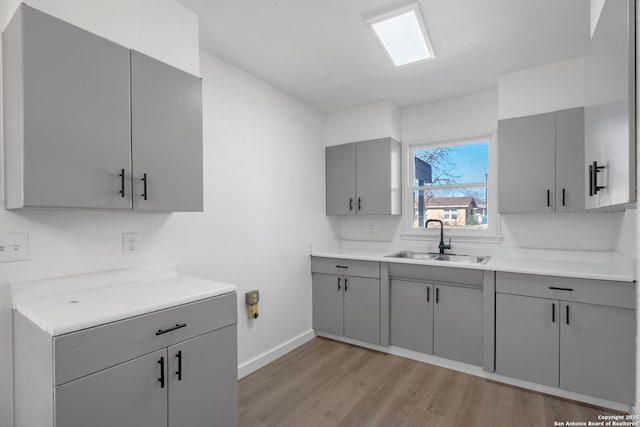 kitchen featuring gray cabinetry, sink, and light hardwood / wood-style flooring