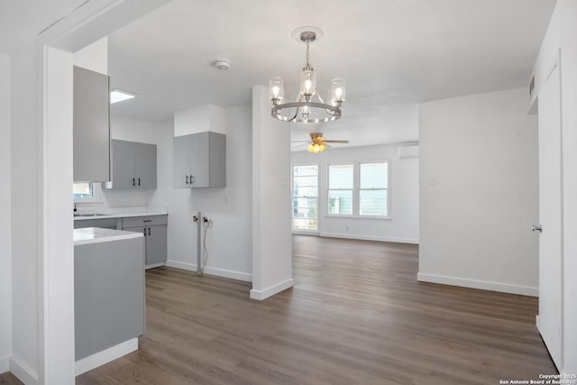 kitchen with gray cabinetry, ceiling fan with notable chandelier, and dark hardwood / wood-style floors