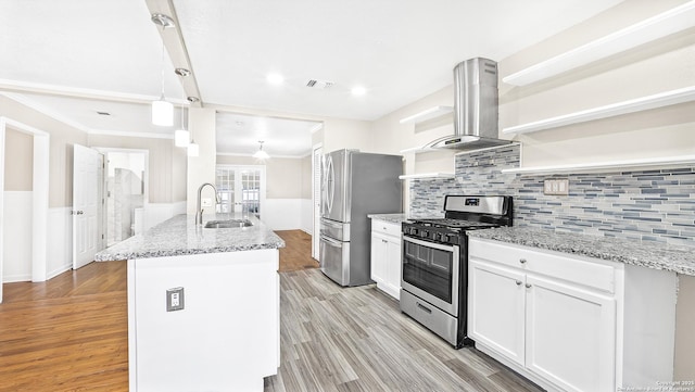 kitchen with appliances with stainless steel finishes, pendant lighting, island range hood, white cabinetry, and a center island with sink