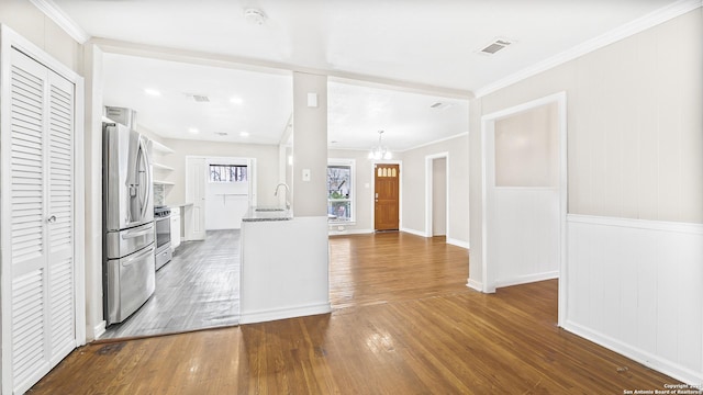 kitchen featuring crown molding, stove, hardwood / wood-style floors, stainless steel refrigerator with ice dispenser, and white cabinets