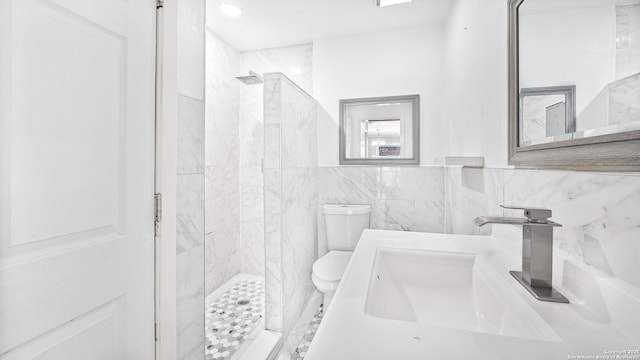 bathroom featuring tiled shower, toilet, sink, and tile walls