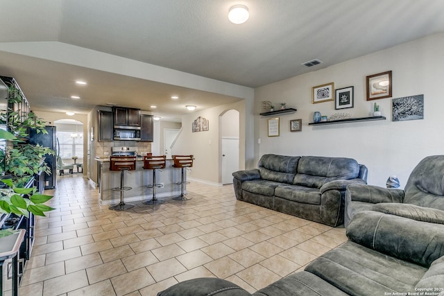 living room with light tile patterned flooring and vaulted ceiling