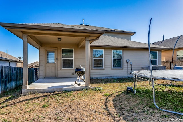 rear view of house with a patio, a trampoline, and a lawn