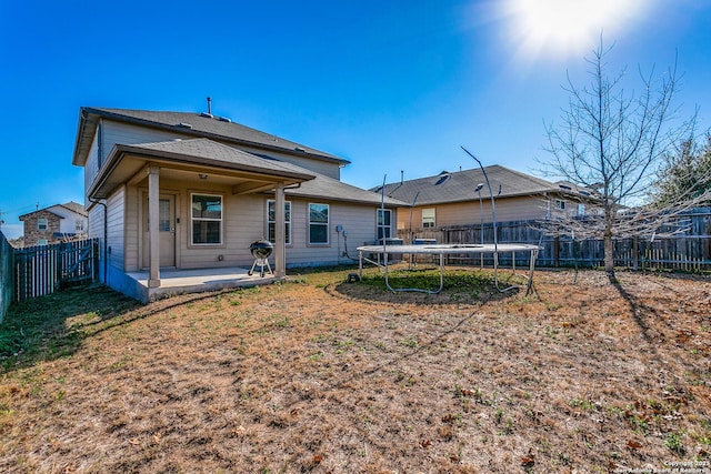 rear view of property featuring a trampoline and a patio area