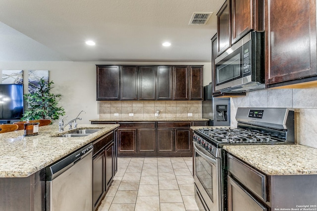 kitchen with an island with sink, stainless steel appliances, sink, and dark brown cabinets