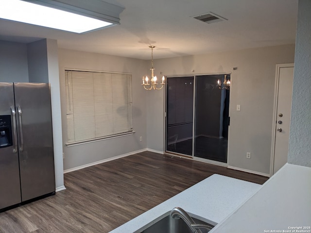 kitchen featuring pendant lighting, a notable chandelier, stainless steel fridge, and dark hardwood / wood-style flooring