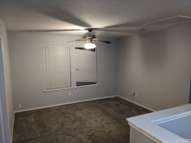 unfurnished room featuring ceiling fan, a textured ceiling, and dark colored carpet