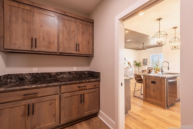 kitchen with pendant lighting, stainless steel dishwasher, kitchen peninsula, and dark stone countertops