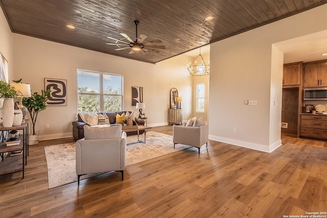 living room featuring ceiling fan with notable chandelier, hardwood / wood-style floors, and wooden ceiling