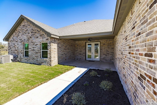 view of exterior entry with a patio, cooling unit, a yard, ceiling fan, and french doors