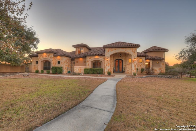 mediterranean / spanish-style house featuring a lawn and french doors