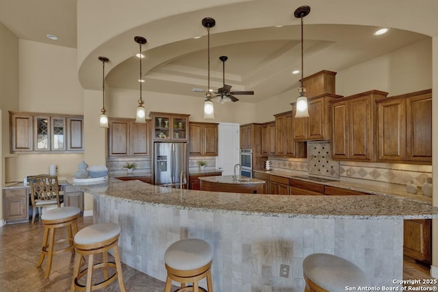 kitchen with a spacious island, a breakfast bar area, hanging light fixtures, stainless steel appliances, and light stone countertops