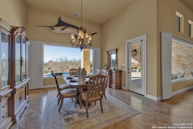 tiled dining area with a chandelier and a high ceiling