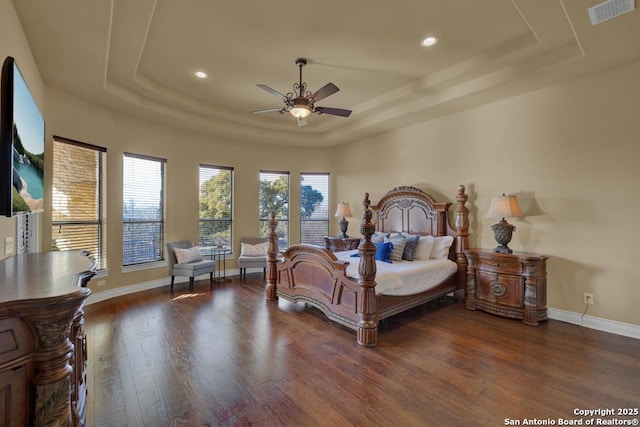 bedroom with dark hardwood / wood-style floors and a raised ceiling