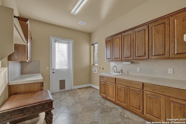 kitchen featuring sink, decorative backsplash, and tile countertops