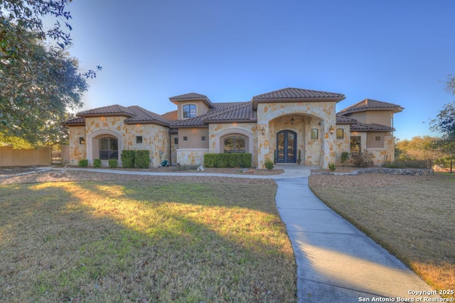 mediterranean / spanish-style house featuring a front lawn and french doors