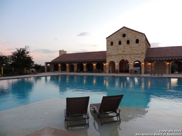 pool at dusk with a patio area