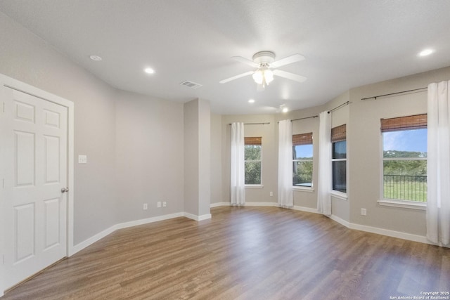 empty room featuring ceiling fan, plenty of natural light, and wood-type flooring