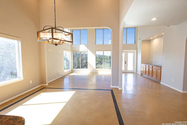 unfurnished room featuring a high ceiling, concrete flooring, and a healthy amount of sunlight