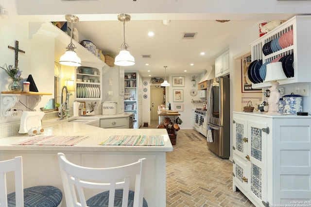 kitchen with appliances with stainless steel finishes, decorative light fixtures, sink, a kitchen bar, and kitchen peninsula