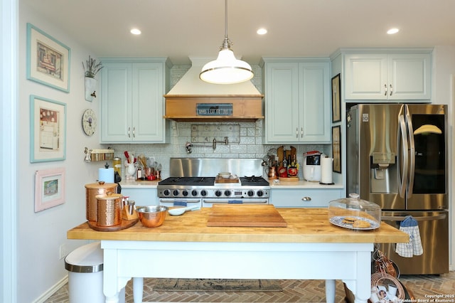 kitchen featuring premium range hood, butcher block countertops, decorative light fixtures, decorative backsplash, and stainless steel appliances