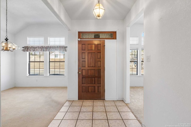 carpeted foyer with lofted ceiling and a chandelier