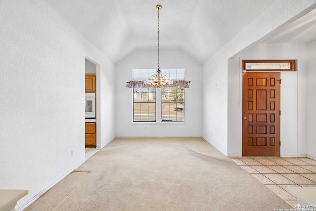 unfurnished dining area featuring an inviting chandelier, vaulted ceiling, and light colored carpet