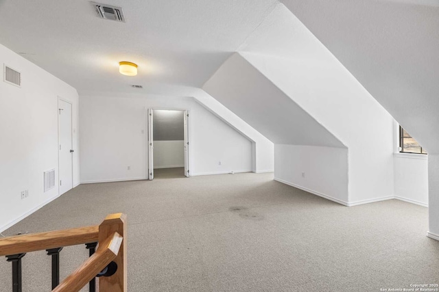 additional living space featuring light carpet and vaulted ceiling