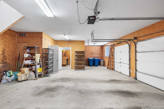 garage with a garage door opener and wood walls