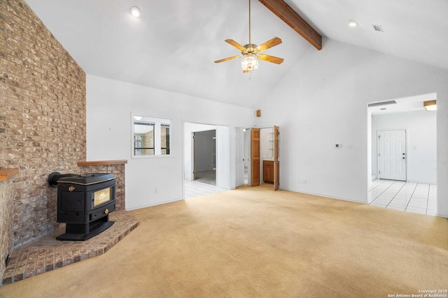 unfurnished living room featuring high vaulted ceiling, beamed ceiling, a wood stove, light colored carpet, and ceiling fan